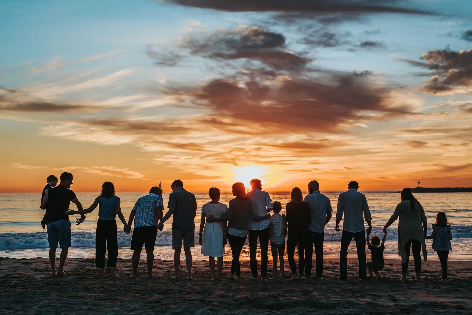 Three generations of a family walking together outdoors at sunset